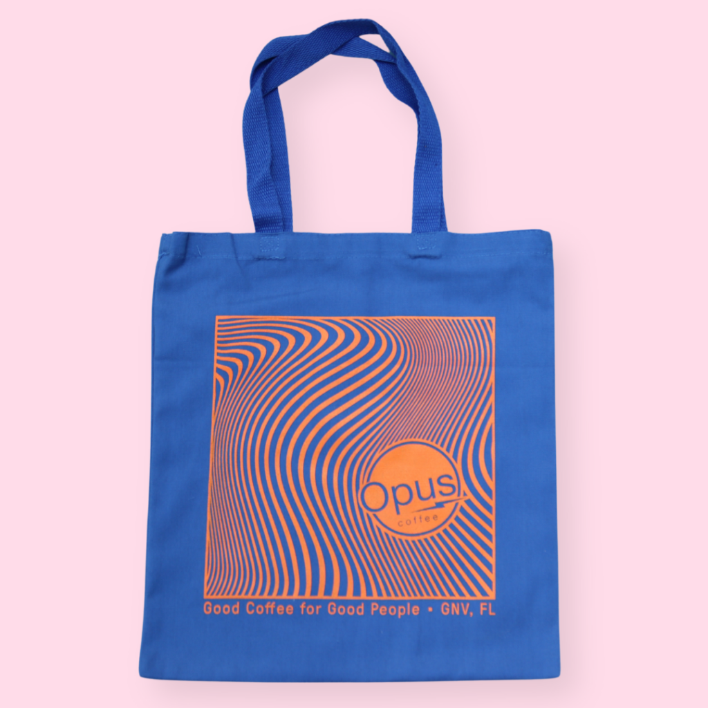 Blue tote bag with orange wavy Opus design. Tote bag says Opus Coffee with "Good Coffee for Good People" on the bottom.