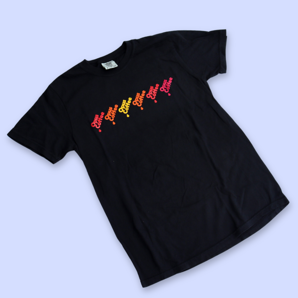 Black T-shirt with Opus drip logo in alternating red, orange, yellow colors.