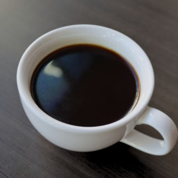 Americano in a white mug on a brown table.
