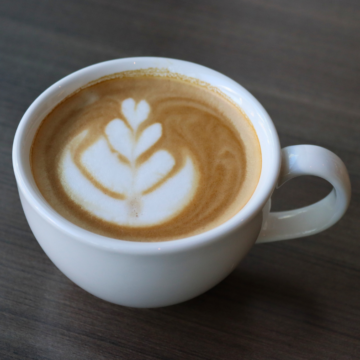 Cappuccino in a white mug with a rosetta latte art.