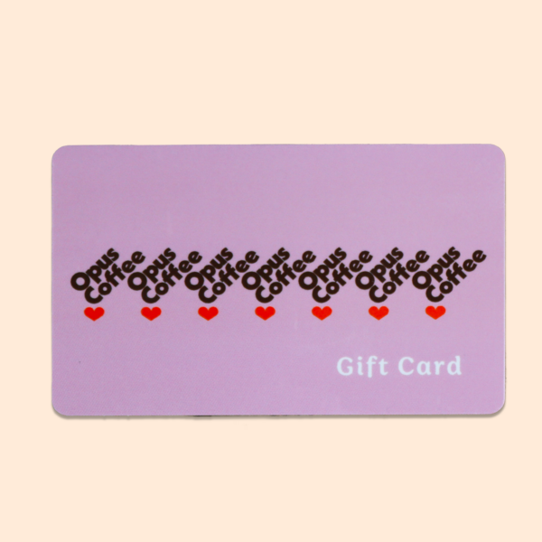 Opus Coffee heart drip logo on pink gift card with beige background.