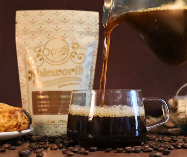 Noteworthy Colombia from Opus bag pictured next to a scone and black coffee being poured into a clear glass mug.