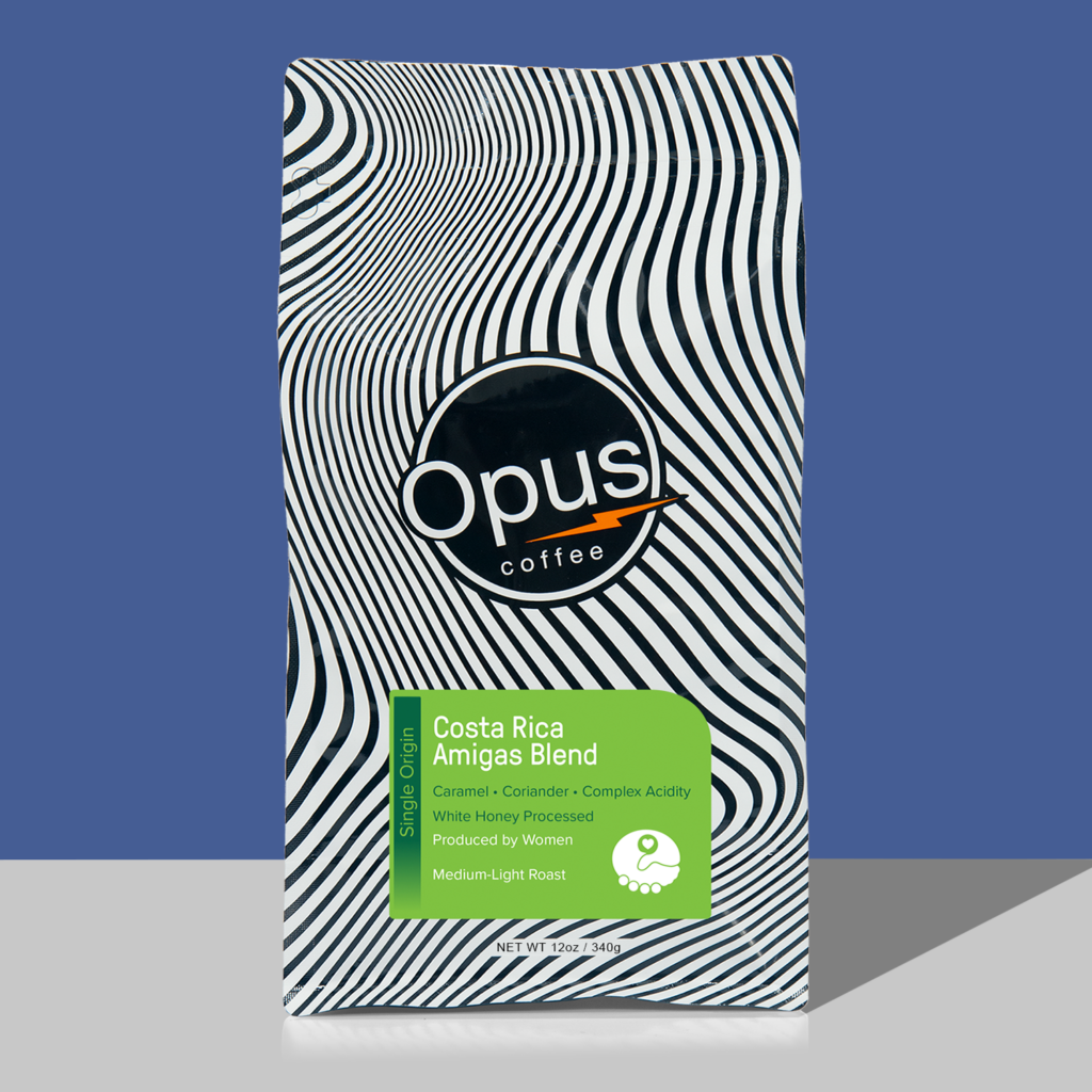Opus coffee retail bag with light green label that reads, "Costa Rica Amigas Blend" and cupping notes. The bag is on a blue background.