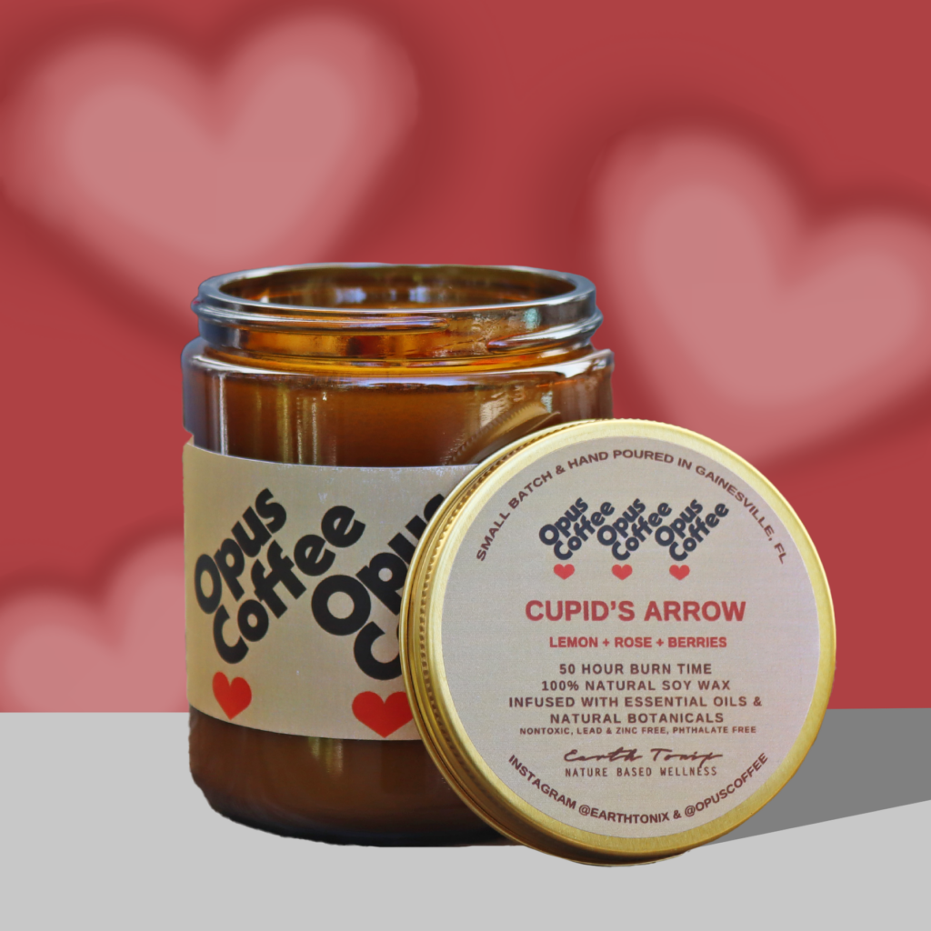 Cupid's Arrow candle with a red and pink hearts background.