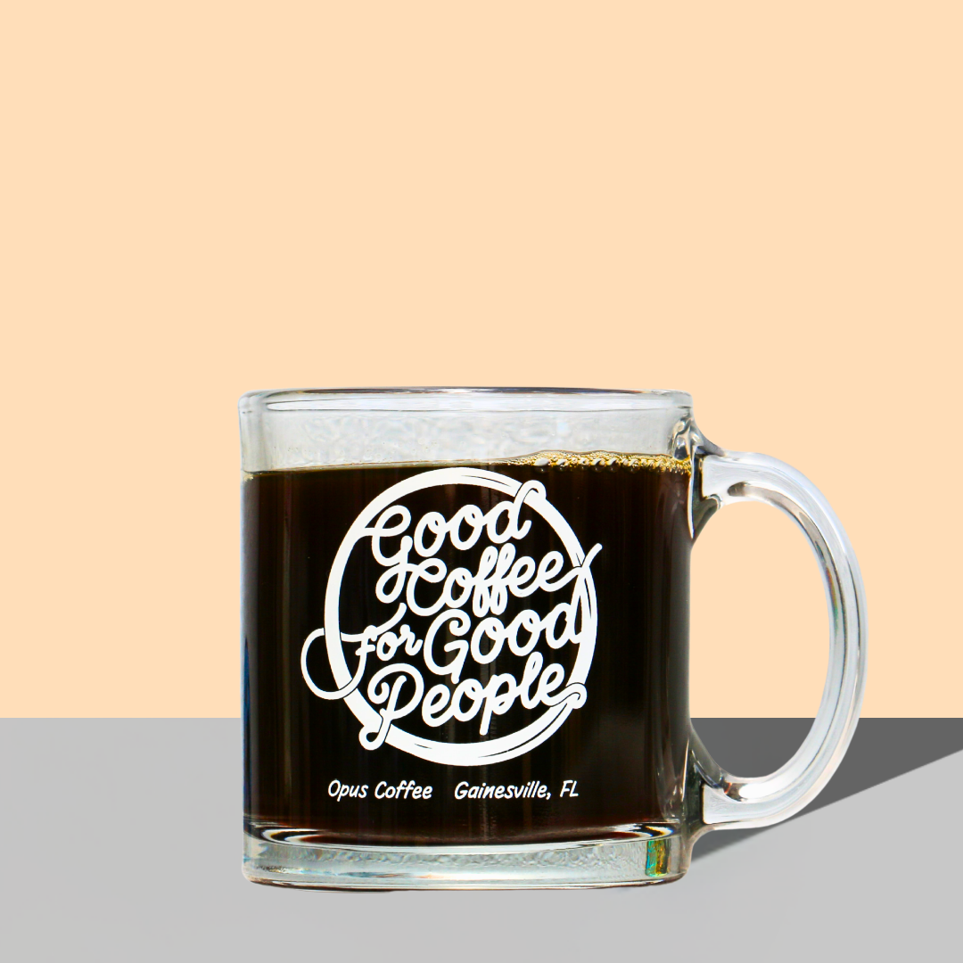 clear glass mug that reads "good coffee for good people" in a cursive font. The mug is on an orange and gray background.