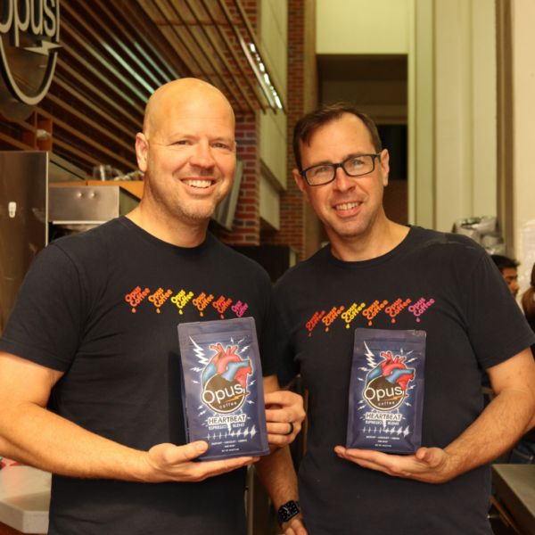 The two founders of Opus Coffee, brothers Tim and Bret Larson pictured in front of the flagship Atrium location at UF Health. They are holding the newly named Heartbeat Espresso Blend bag.