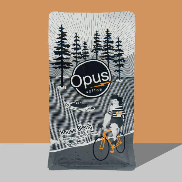 Opus coffee house blend coffee bag that features a person riding a bike in a Gainesville nature theme on an orange background.