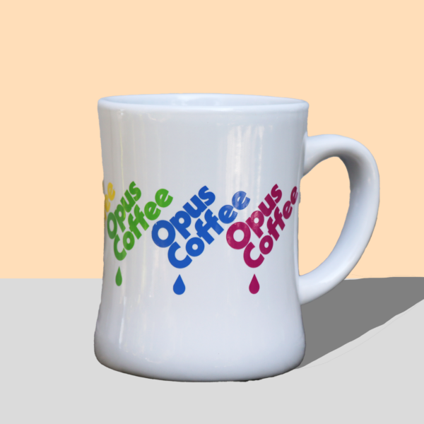 White diner mug with Opus Coffee drip logo in Pride rainbow colors wrapped around it.