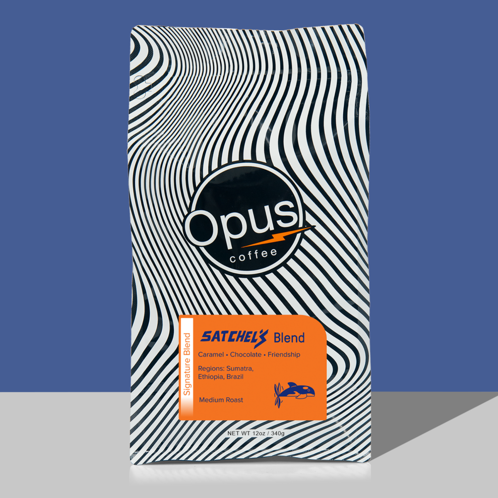Opus coffee retail bag black and white wavy design with orange label that reads, "Satchel's Blend" and cupping notes. The bag is on a blue background.