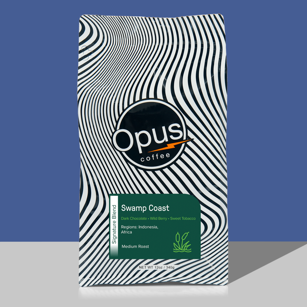 Opus coffee retail bag with green label that reads, "Swamp Coast Blend" and cupping notes. The bag is on a blue background.