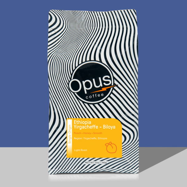 white and black retail coffee bag of Opus Coffee's Ethiopia Yirgacheffe - Biloya coffee. Bag has a yellow label and bag is photographed on a light blue back drop.
